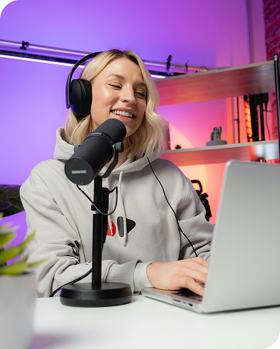 Perempuan menggunakan mikrofon dan laptop di studio dengan pencahayaan ungu